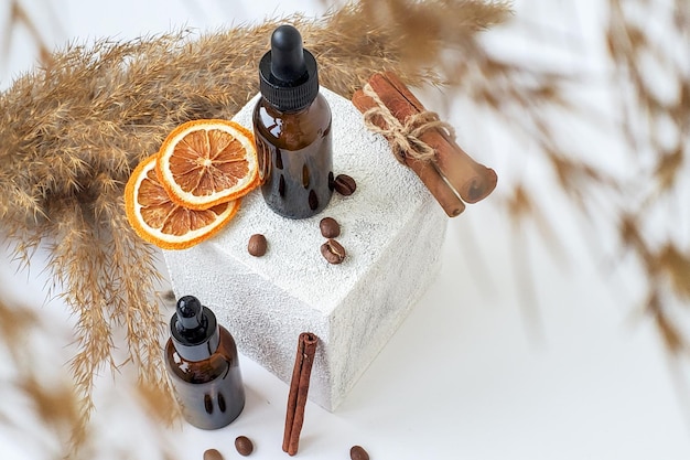 Beauty background, oil bottles, podium, orange, coffee, dry grass.