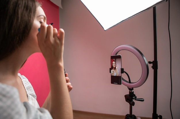 Beauty blogger recording makeup tutorial on phone camera