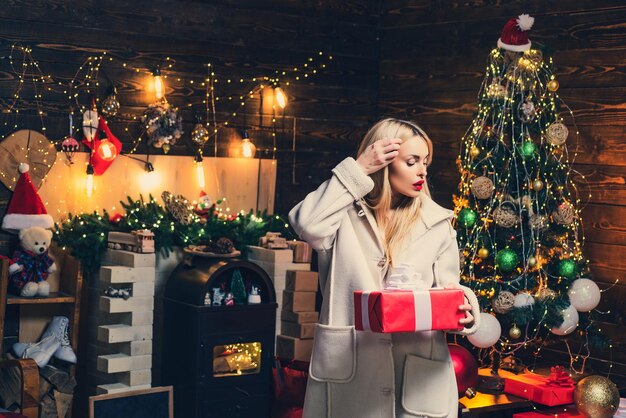 Beauty Christmas fashion model girl holding xmas gift box. Beautiful happy woman with gift box at celebration party. Wish you merry Christmas.