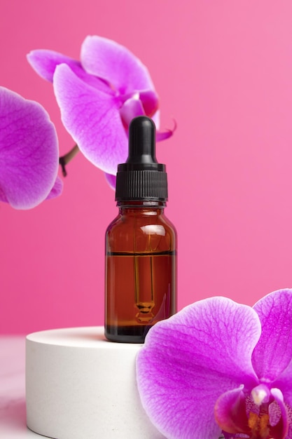 Beauty collagen face oil in a glass dropper bottle on podium with orchid flowers Trendy shoot of cosmetics packaging Essential oil with natural ingredients