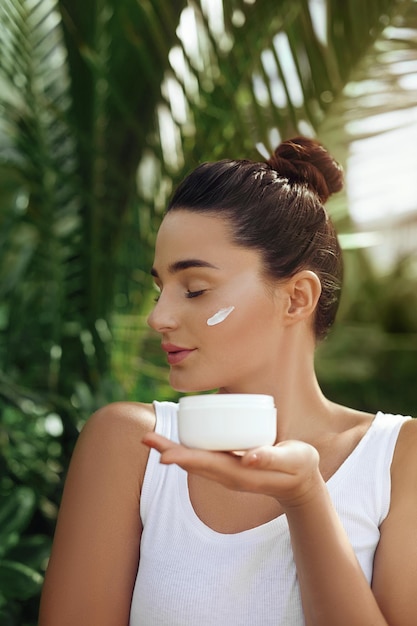 Beauty Concept Woman Holds Cosmetics Cream Portrait of Girl in Tropical Leaves Body And Skin care