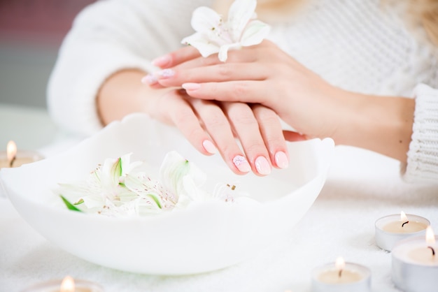 Beauty delicate hands with manicure holding flower lily.