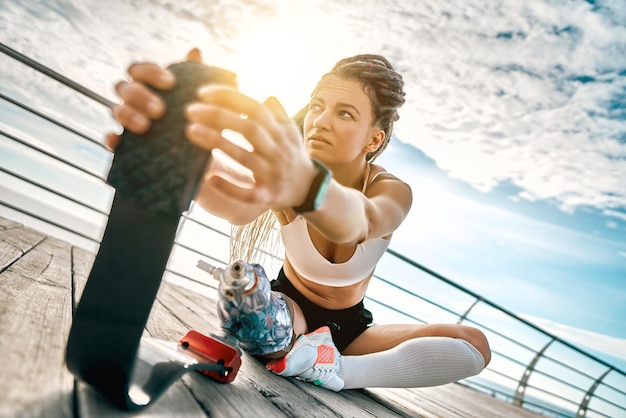 Photo beauty disabled athlete woman with prosthetic leg doing stretching exercises while sitting on bridge