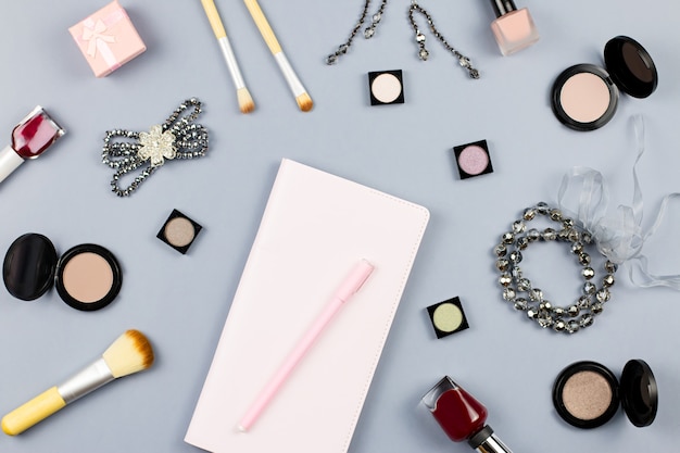 Beauty, fashion blogger concept. Fashion accessories, note book and cosmetics on grey surface flat lay.