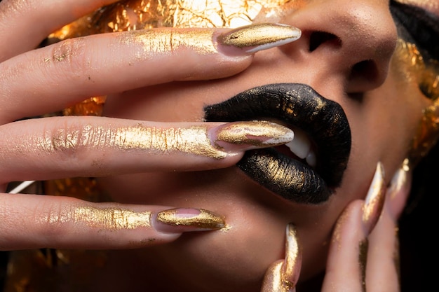 Beauty fashion model girl with golden makeup and body on black background Golden body art