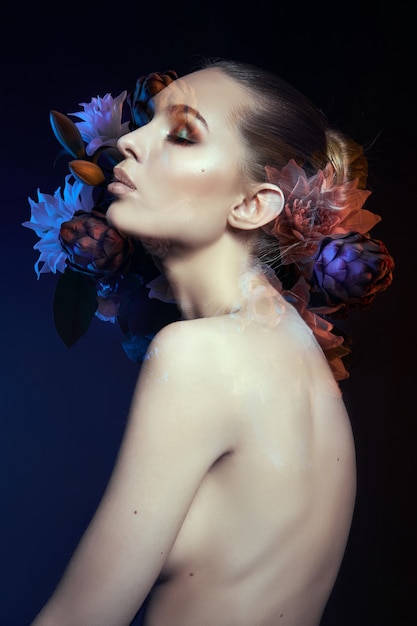 Beauty flowers face of a woman with double exposure. Portrait of a girl neon light and color, professional makeup, nude back of a woman, flowers in the head