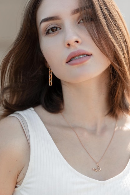 Beauty gentle female portrait of a beautiful young girl with freckles and brackets teeth with a pretty face and brown eyes on a summer sunny day Fresh amazing woman