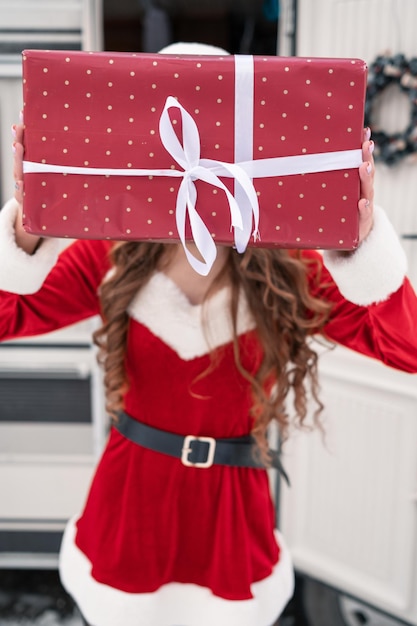 Beauty girl in santa costume with gift box at winter campsite getting ready for the new year new yea