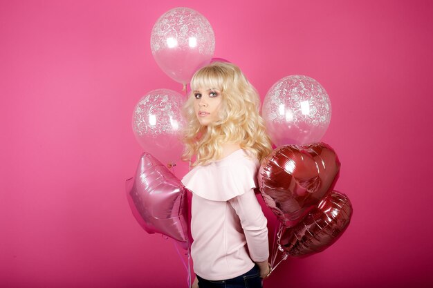 Photo beauty girl with air balloon laughing over pink background. beautiful happy woman