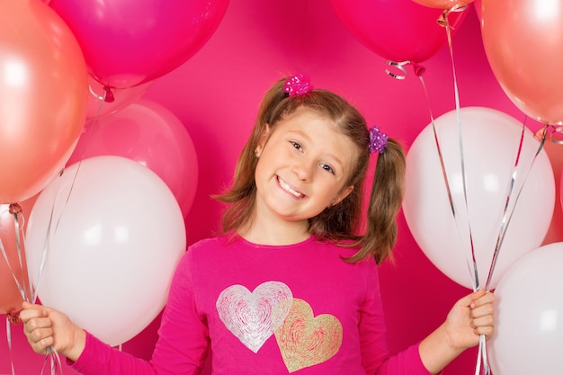 Beauty girl with colorful air balloons smiling over pink