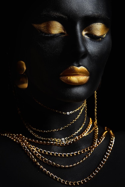 Beauty gold makeup lips eyelids woman black skin color body art gold jewelry chain fingertips nails in gold color paint Professional gold makeup