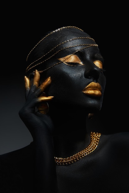 Beauty gold makeup lips eyelids woman black skin color body art gold jewelry chain fingertips nails in gold color paint Professional gold makeup