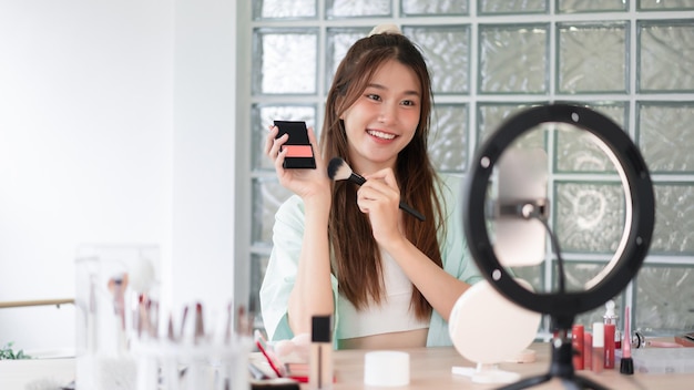 Beauty influencer concept Young woman apply blusher to introduce product and record video for Vlog