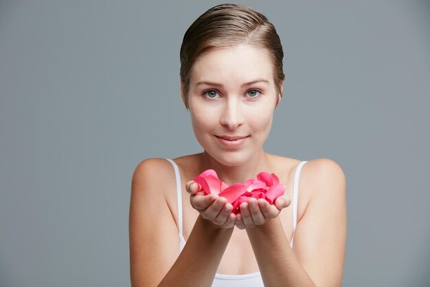 Beauty inspired by the softness of petals Studio portrait of an attractive young woman holding a handful of pink petals against a gray background