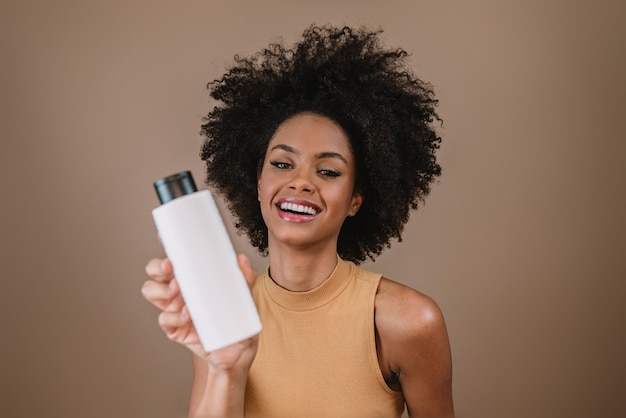 Beauty Latin woman with afro hairstyle Brazilian woman Holding blank shampoo packaging