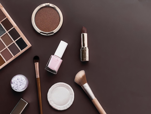 Beauty makeup and cosmetics flatlay design with copyspace cosmetic products and makeup tools on brown background girly and feminine style