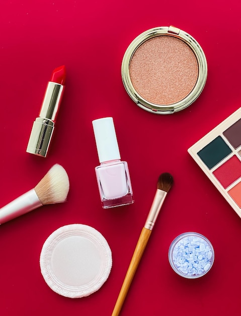 Beauty makeup and cosmetics flatlay design with copyspace cosmetic products and makeup tools on red background girly and feminine style concept