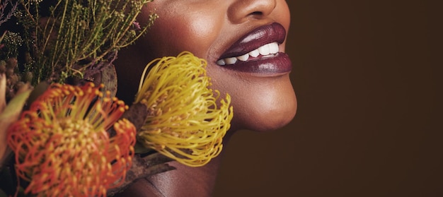 Beauty makeup and plants with lips of black woman in studio for natural spa and mockup space Cosmetics flowers and closeup with model on brown background for sustainability glow and banner