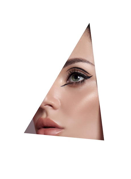 Beauty makeup women, eye brows eyelashes and lips in a triangular hole paper white background. Professional beauty makeup, place for text, copy space