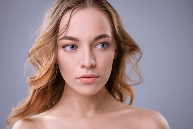 Beauty model young blonde woman with blue eyes with natural make-up and healthy skin on a white background