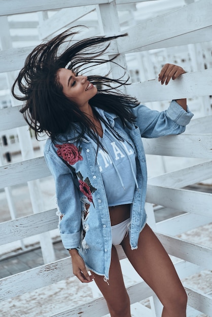 Beauty in motion.  Attractive young mixed race woman in jeans shirt shaking her head and smiling while standing outdoors