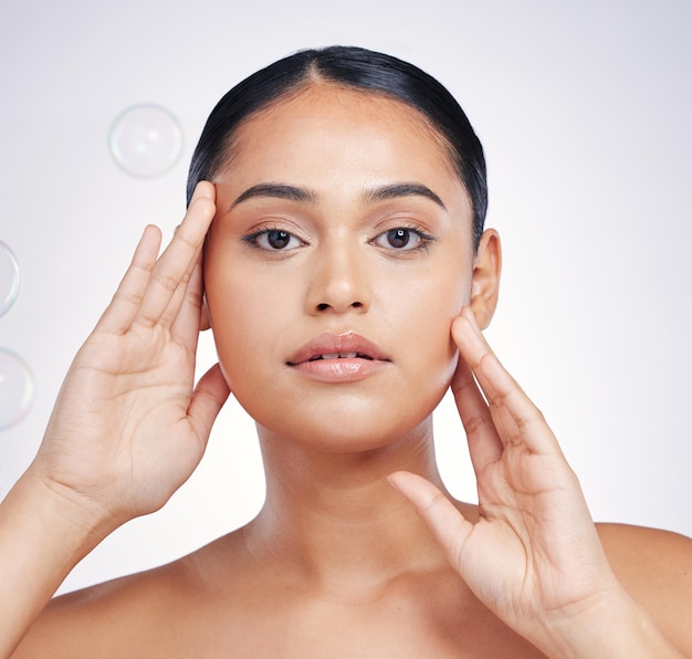 Beauty natural and woman with hands on face in studio for glow skin dermatology or cosmetic Portrait of aesthetic model person with bubbles for self care facial or skincare on a white background