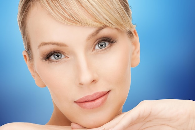 beauty, people and makeover concept - beautiful young woman face over blue background