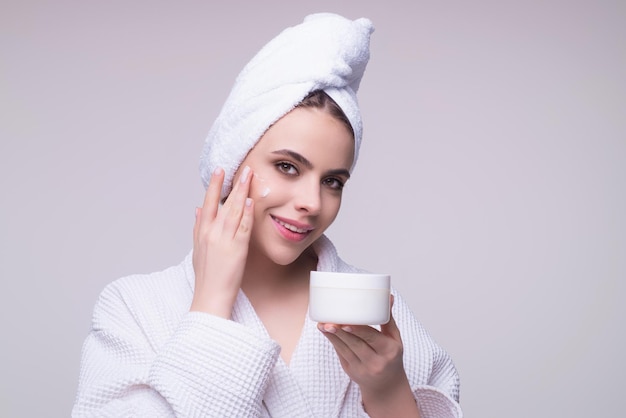 Beauty portrait of a beautiful half naked woman applying face cream isolated on studio background sk