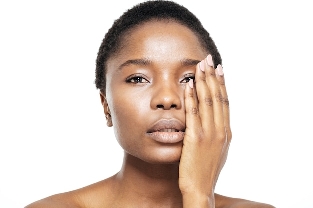 Beauty portrait of a charming afro american woman touching her face with hand isolated on a white background