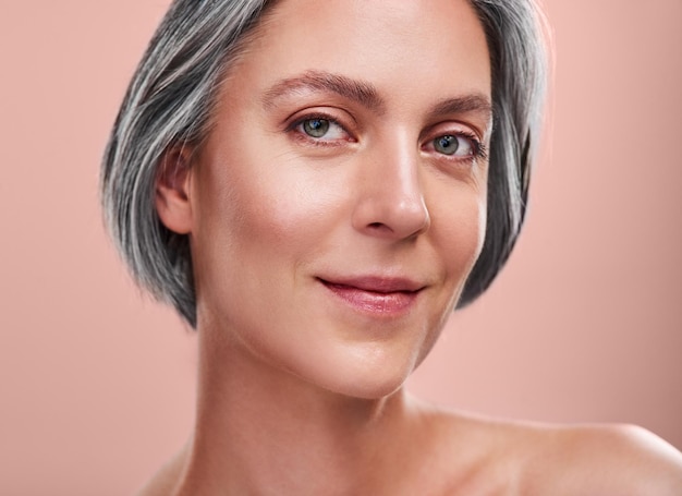 Photo beauty portrait and mature woman with skincare for facial glow and wellness in studio skin health dermatology and female person with collagen cosmetics for anti aging results by pink background