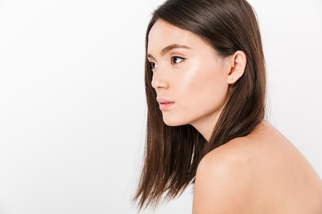 Beauty portrait in profile of half-naked asian woman with brown long hair posing isolated over white