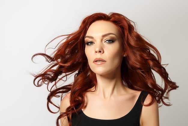 Beauty portrait of a red-haired beautiful woman on a gray background.