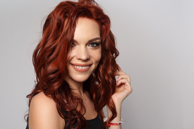 Beauty portrait of a red-haired happy beautiful woman on gray.