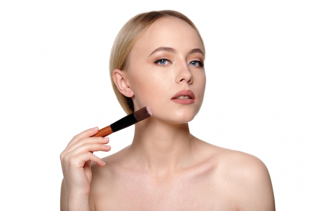 Beauty portrait of a smiling beautiful half naked woman posing with make-up brushes