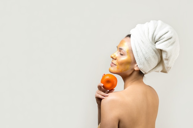 Beauty portrait of woman in white towel on head with gold nourishing mask on face