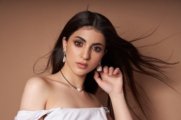 Beauty portrait of a woman with jewelry, earrings in her ears and a necklace around her neck. Perfect clean face skin, natural cosmetics