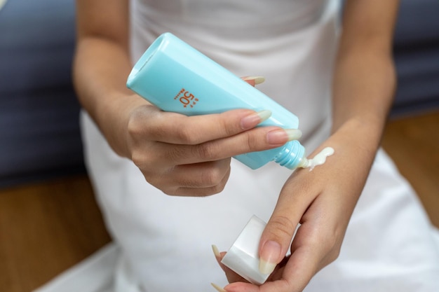 Beauty portrait of young Asian woman applying cream and sunscreen on hand