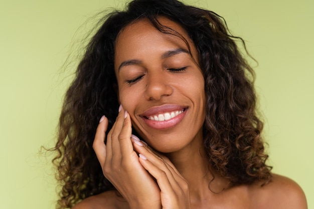 Beauty portrait of young topless african american woman with bare shoulders on green background with perfect skin and natural makeup