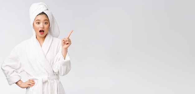 Beauty portrait of young woman showing and pointing finger to empty copy space asian beauty in bathrobe