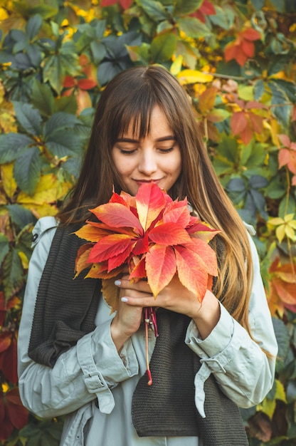 Beauty Romantic woman Outdoors enjoying nature holding leaves in hands. Beautiful autumn model with waving glow hair. Sun light on sunset. Portrait of romantic female