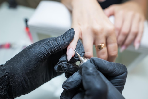 Beauty salon manicure Professional hardware manicure using an electric machine in a beauty salon the master uses an electric machine to remove the cuticle