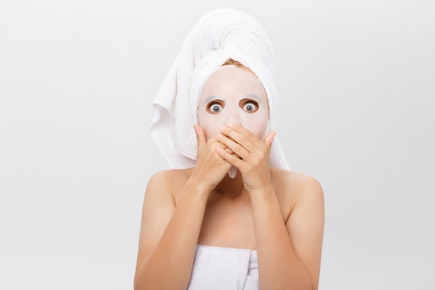 Beauty Skin Care Concept - Beautiful Caucasian Woman applying paper sheet mask on her face white background.