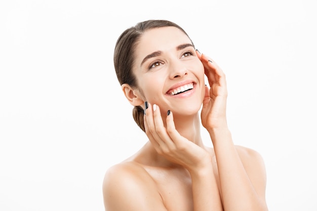 Beauty and Skin care concept - Close up Beautiful Young Woman touching her skin on white wall.