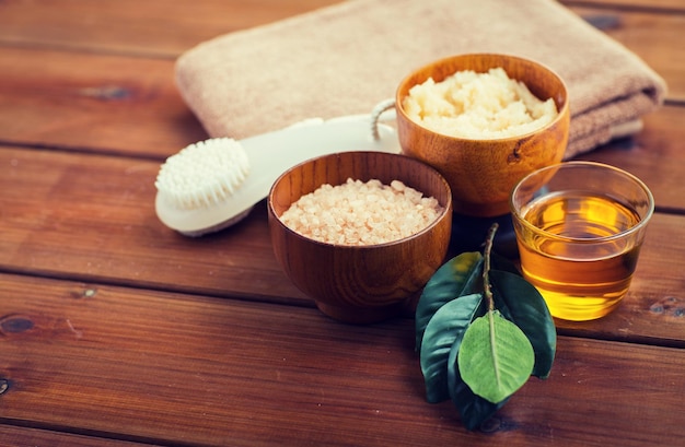 beauty, spa, body care, natural cosmetics and bath concept - close up of himalayan pink salt and body scrub with brush on wooden table