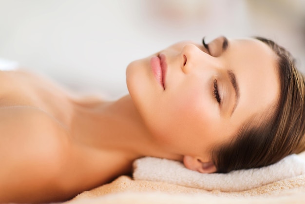 beauty and spa concept - beautiful woman in spa salon lying on the massage desk