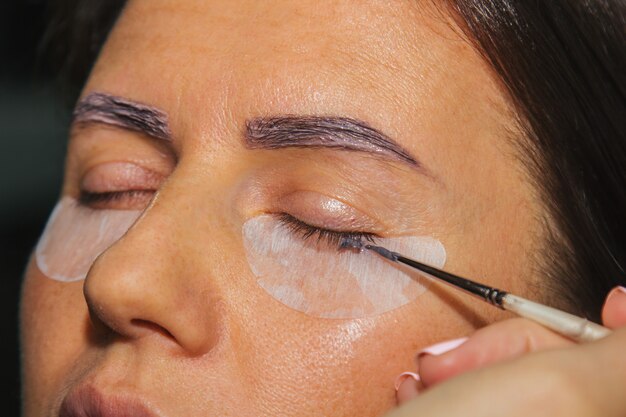 Beauty treatment. Closeup woman's face with paint on eyelashes. laminating eyelashes. Side view.