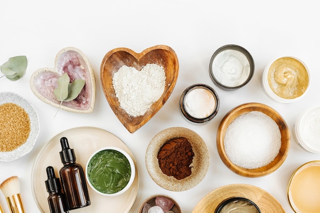 Beauty treatment ingredients for making homemade skin care cosmetic mask. Various bowl with clay, cream, essential oil and natural ingredients  on white table background. Organic spa cosmetic products