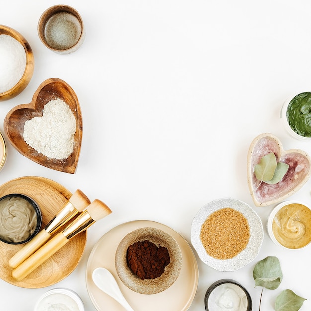 Beauty treatment ingredients for making homemade skin care cosmetic mask. Various bowl with clay, cream, essential oil and natural ingredients  on white table background. Organic spa cosmetic products