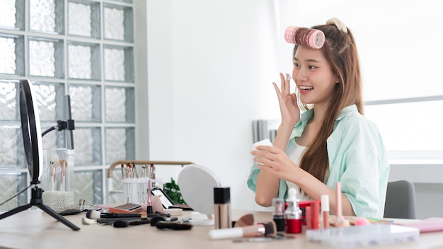 Beauty Vlogger concept Young woman applying moisturizer cream on face to introduce product on Vlog