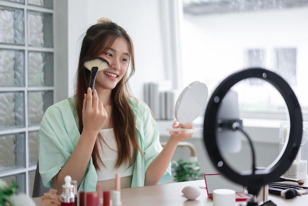 Beauty Vlogger concept Young woman use brush to applying blush on cheek and review product in Vlog